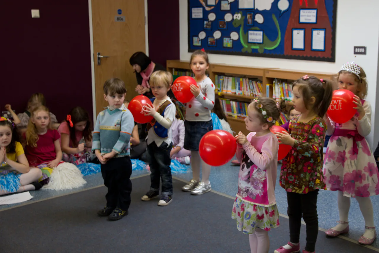 Children holding balloons during a classroom celebration.
