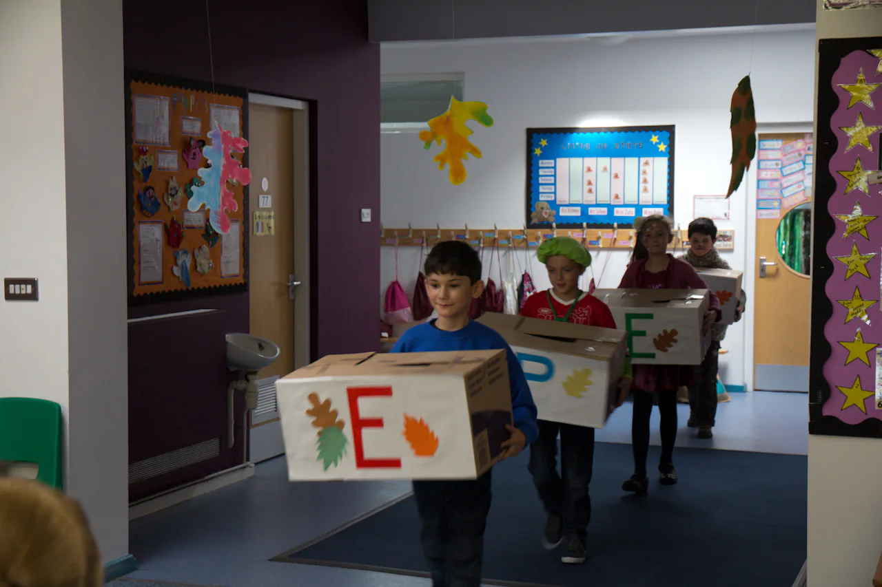 Children carrying letter props through a school corridor.
