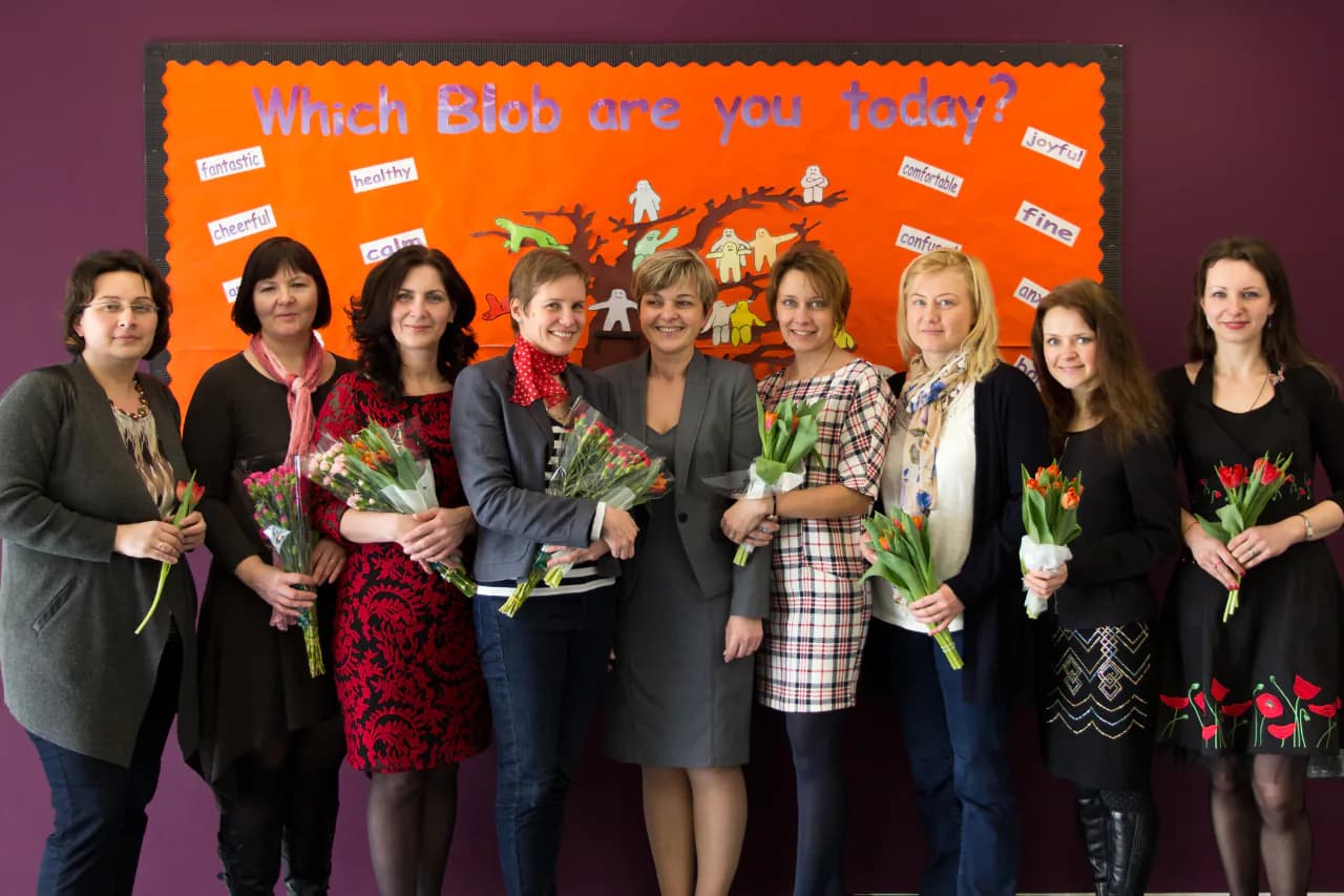 Staff members holding flowers during a school celebration.