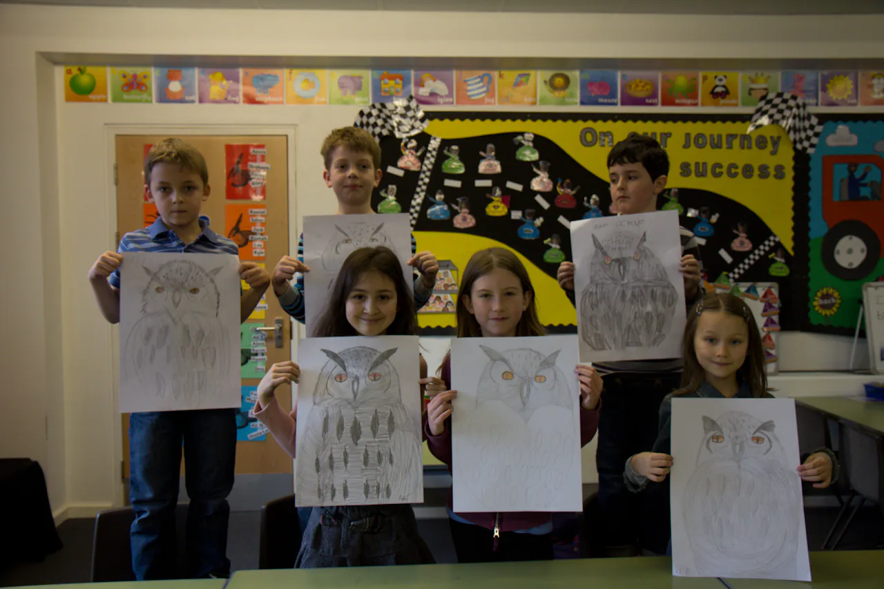 Children holding drawings made during a creative classroom activity.