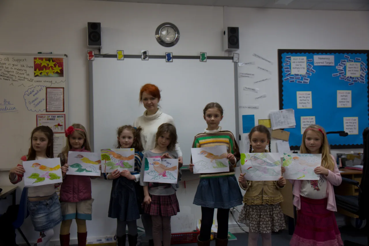 Children holding artwork from a classroom drawing activity.