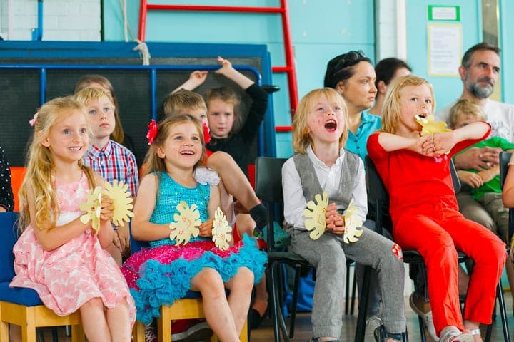 Children seated in costumes during a festive school event.