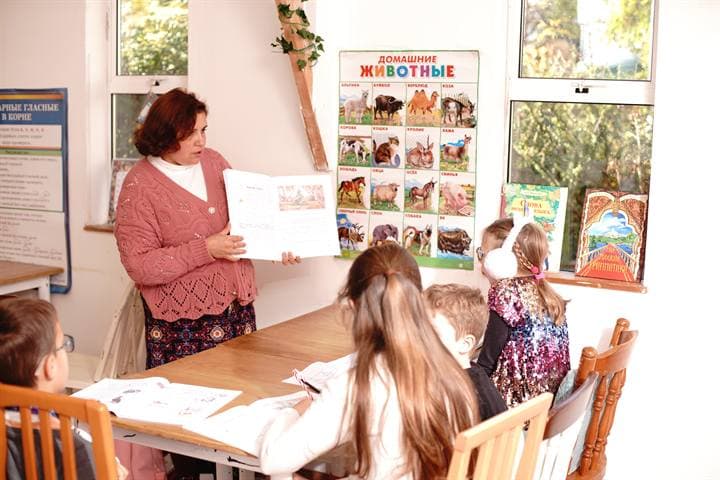 A teacher reading with children in a classroom setting.