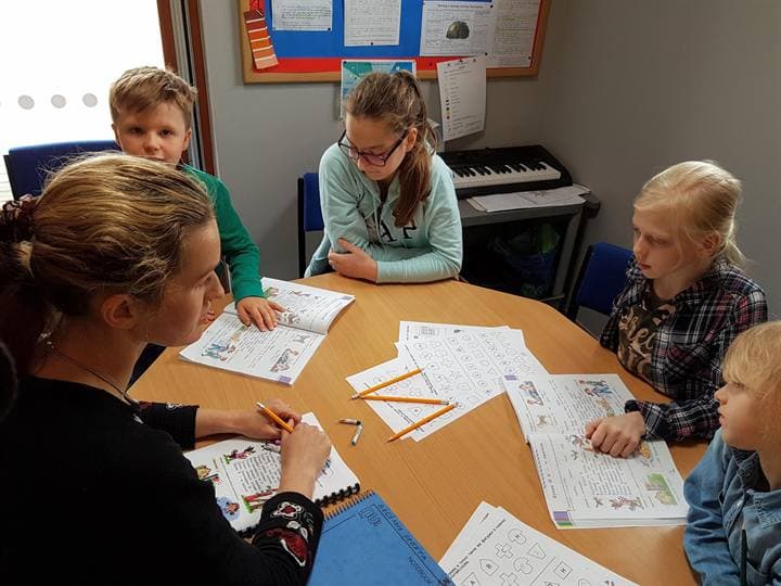 Children working with a teacher around a classroom table.