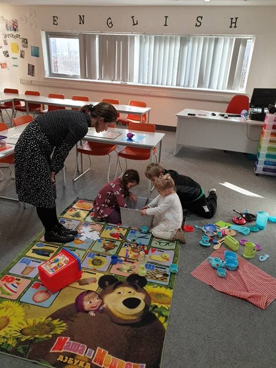 A teacher helping children with a hands-on classroom activity.