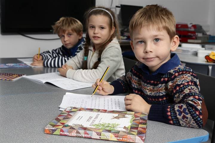 Children working at tables in a classroom setting.