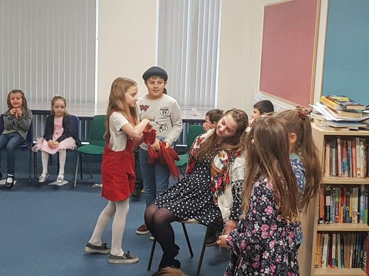 Children and adults gathered in a classroom community setting.
