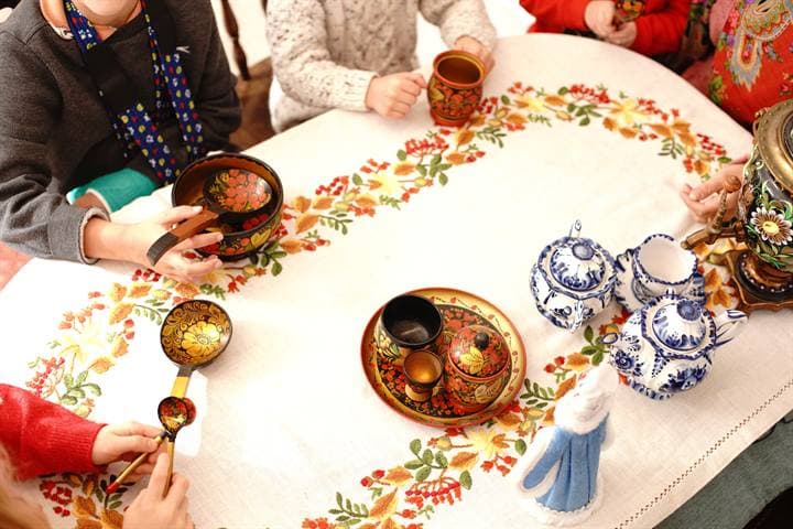 Russian cultural objects and craft materials arranged on a classroom table.