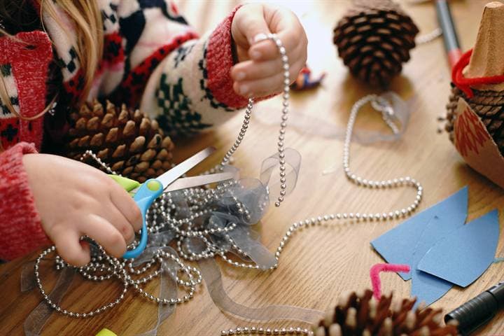 Hands and craft materials on a classroom table.