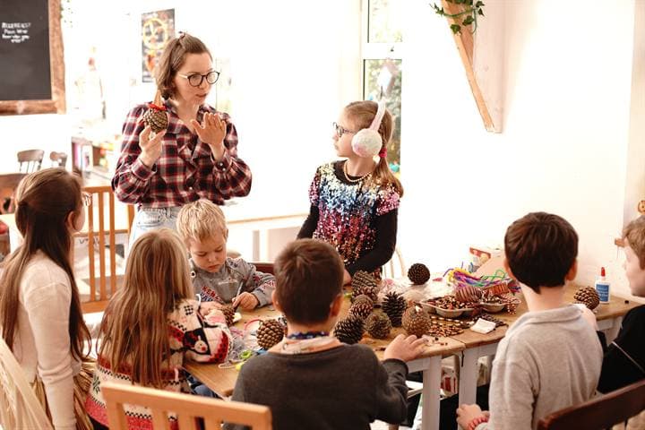 Children gathered around a classroom craft table with a teacher.