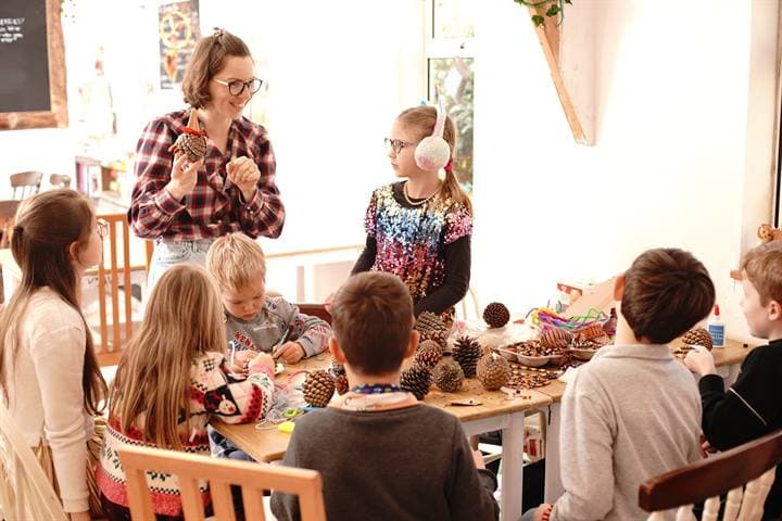 A teacher leading a creative classroom activity with children seated around a table.