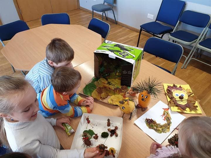 Children working with autumn craft materials at a classroom table.