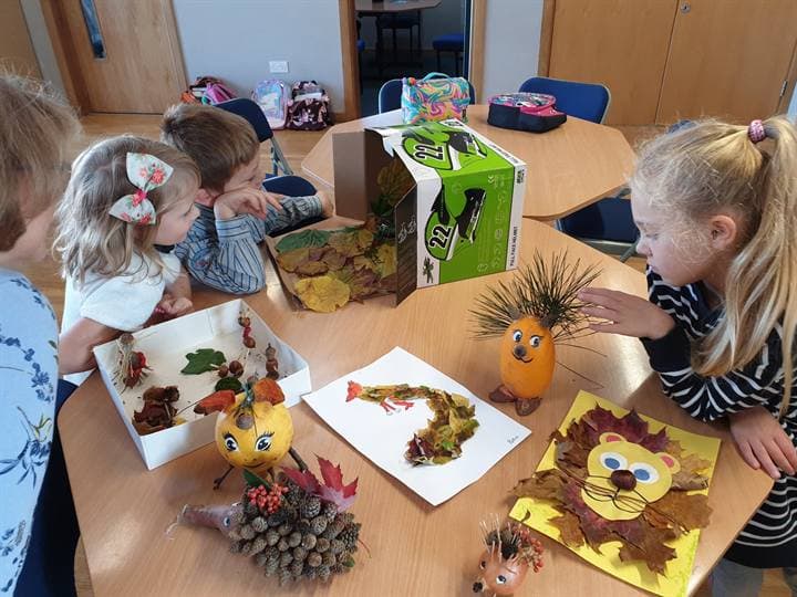Children gathered around an autumn craft display.