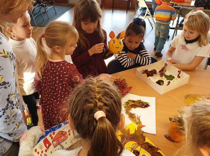 A teacher and children looking at classroom craft work.