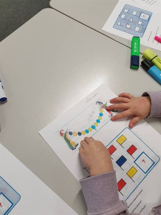 Children working with pattern and colour materials at a table.