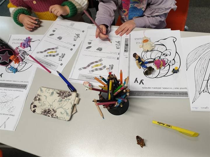 Drawing and craft materials spread across a classroom table.