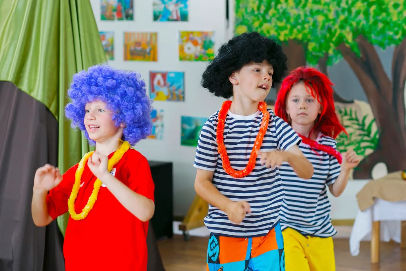 Children in colourful wigs performing as comedy characters.