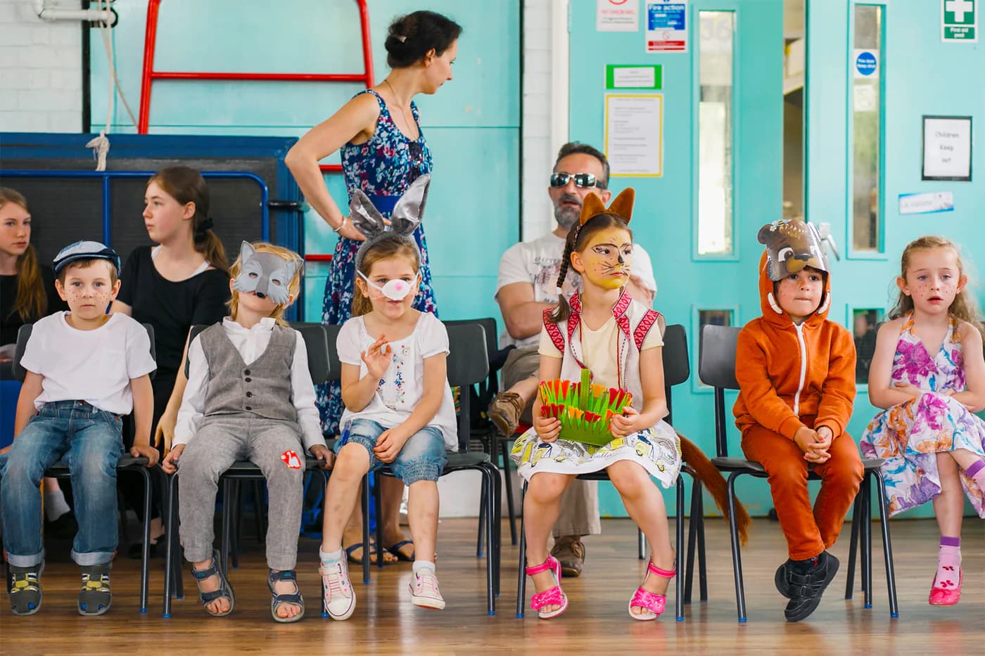 Children in costume seated before a school performance.