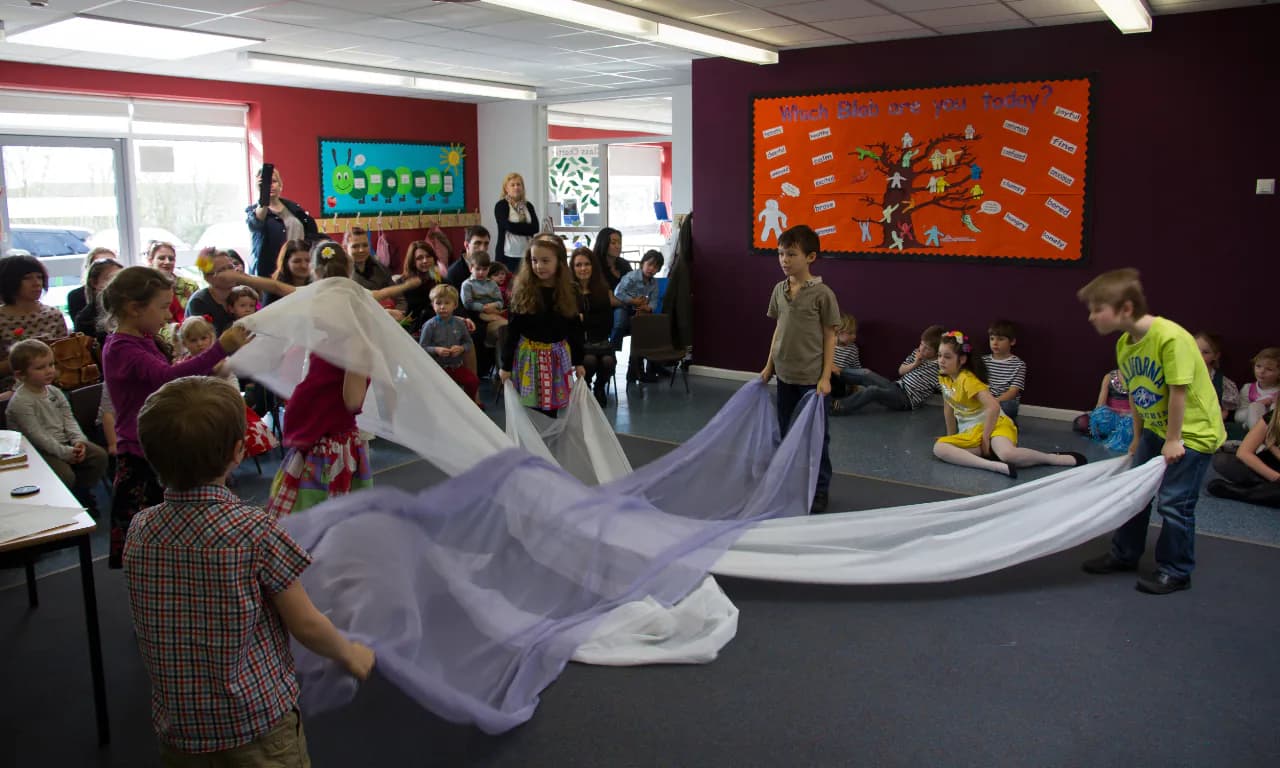 Children performing with fabric during a school event.