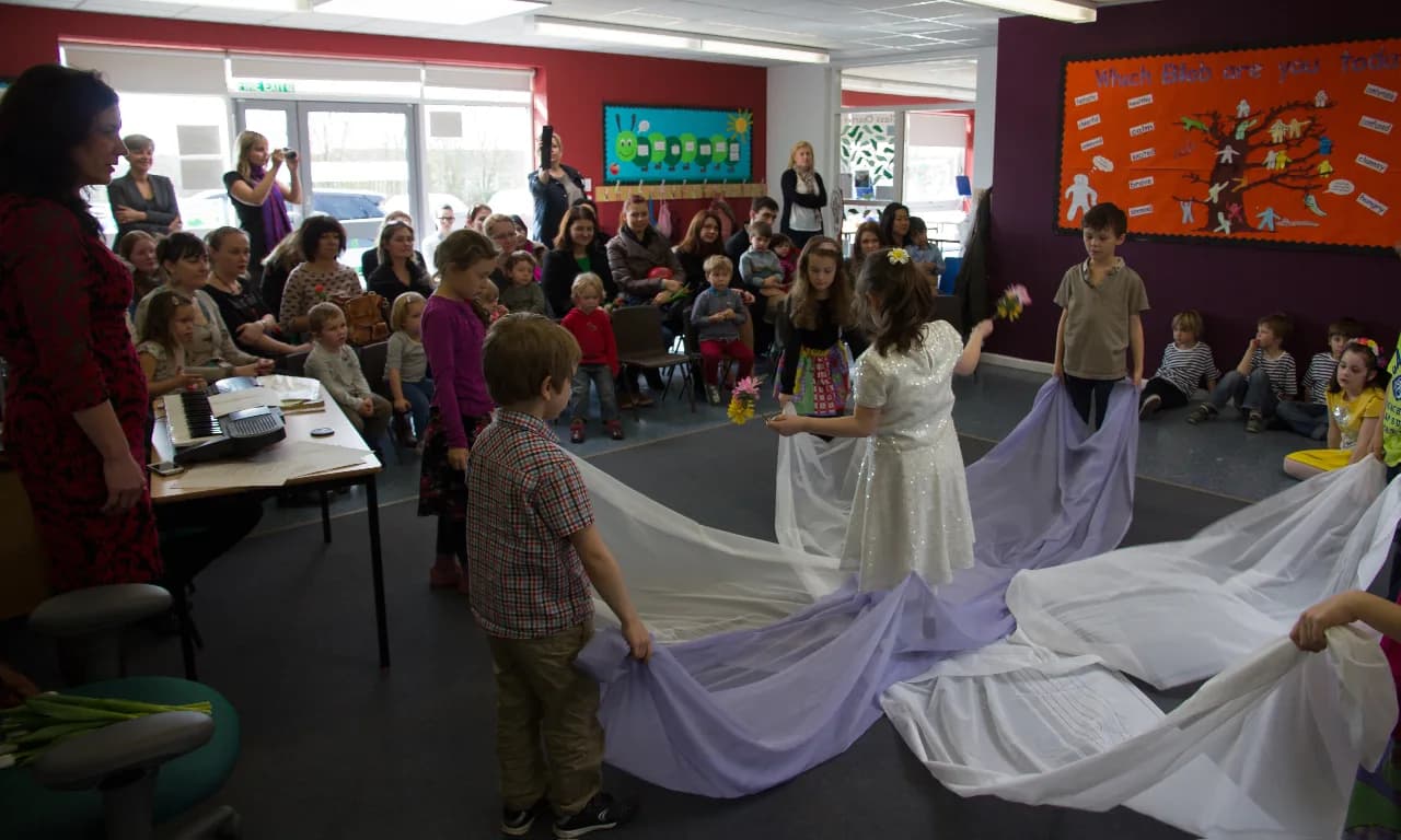 Children and families gathered around a fabric performance activity.