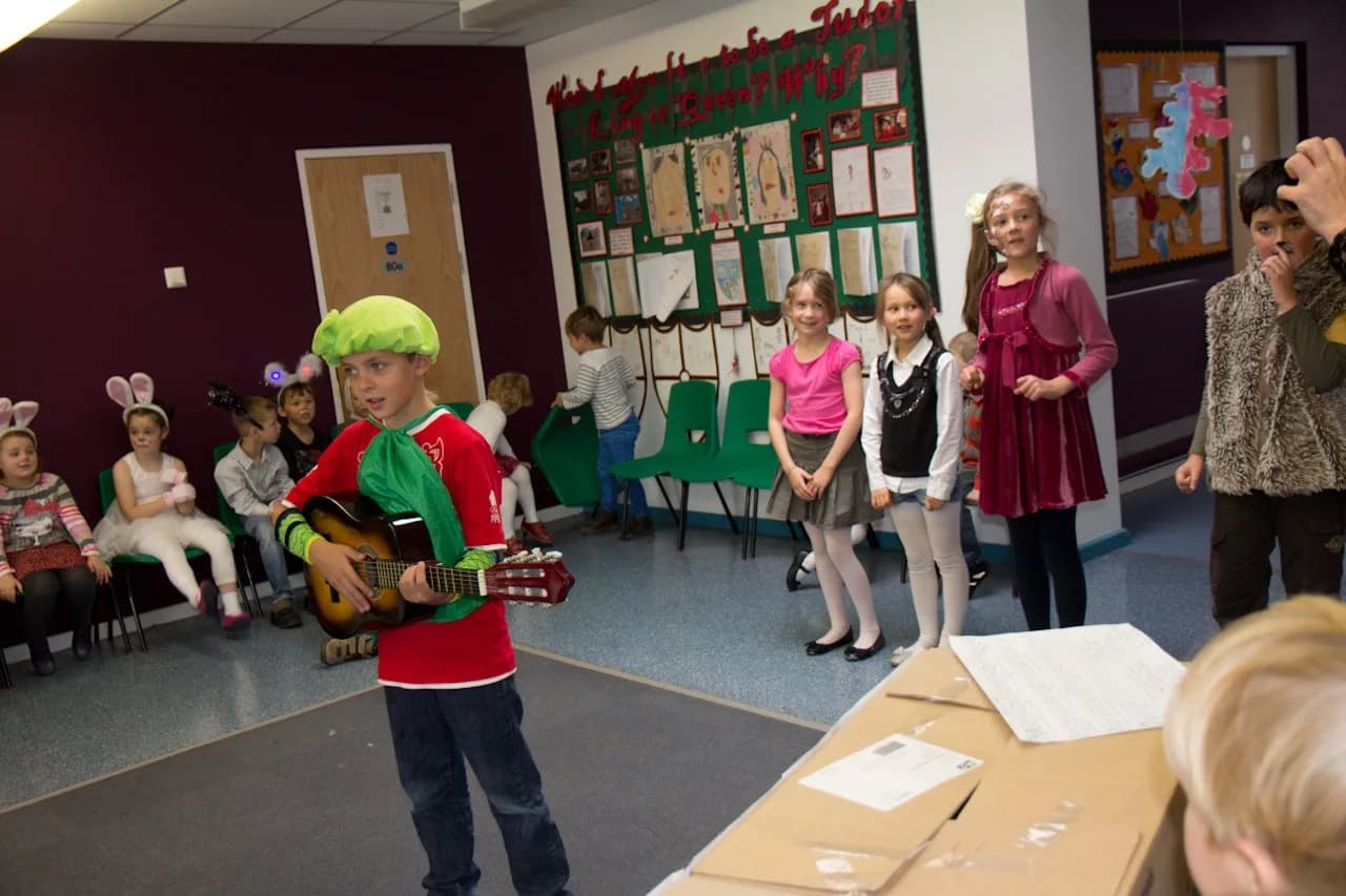 A child performing with a guitar during a classroom recital.