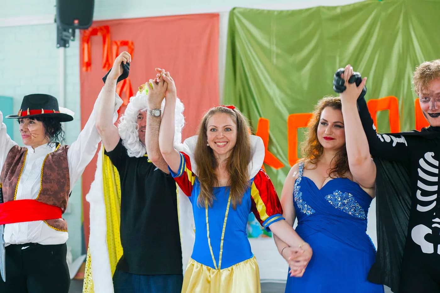 Adult performers taking a curtain call after a school theatre performance.