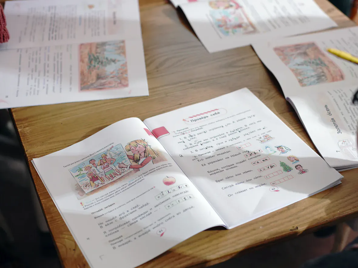 A Russian language workbook open on a classroom table.